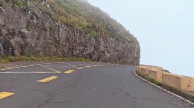 Sisli bir dağ yolu kayalık bir uçurum boyunca kıvrılır ve doğada nefes kesici ve maceralı bir yolculuk sunar.