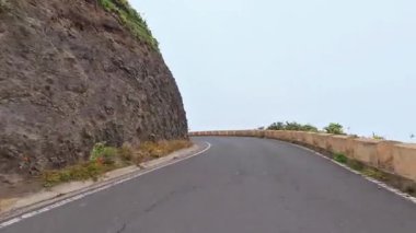 Güzel, dolambaçlı bir yol engebeli kayalık bir uçurum boyunca ilerliyor, yoğun sis ve canlı yemyeşil bir yer ile kaplı.