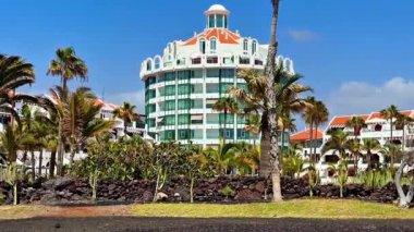 Çarpıcı bir tropikal tatil köyü. Uzun palmiye ağaçları, modern mimari tasarım ve nefes kesici mavi gökyüzü.