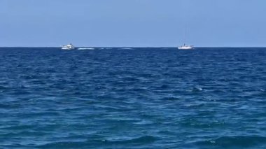 Huzurlu bir okyanus manzarası. Çeşitli tekneleri tasvir ediyor. Sakin, sakin mavi sularda zarifçe geziniyorlar.