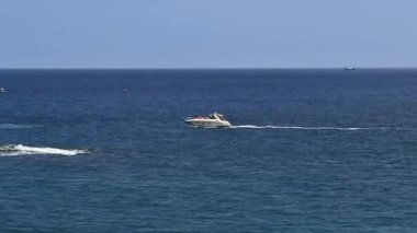 Göz kamaştırıcı ve zarif bir sürat teknesi berrak bir gökyüzünün altında zarif mavi okyanus dalgaları üzerinde süzülüyor.