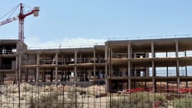 Gelişmekte olan büyük bir binası olan yoğun bir inşaat alanı, bir vinç ve çalışan ekipmanlar.