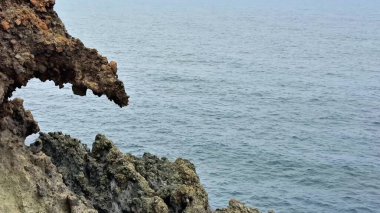 Güzel ve sakin bir sahil manzarası sakin okyanus suyunun yanında sıradışı kayalık bir çıkıntı sergiliyor.