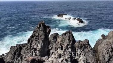 Kayalık sahil şeridinin çarpıcı manzarası okyanus dalgalarının kıyıya çarptığını gösteriyor.