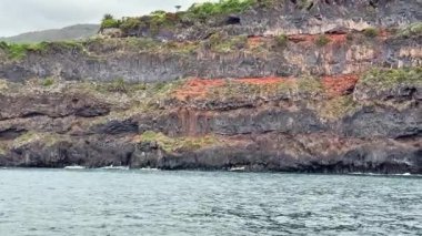 Katmanlı uçurumların olduğu şaşırtıcı derecede güzel bir kıyı manzarası zengin renkler ve sudaki yansımaları sergiliyor.