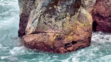 Güçlü dalgaların onlara çarptığı canlı kıyı kayalarının nefes kesici ve çarpıcı görüntüsü.