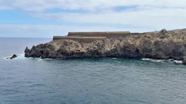 Antik bir sahil kalesinin nefes kesici ve manzaralı manzarası engin denizin kıyısındaki kayalık bir uçurumun tepesinde güzelce tünemişti.