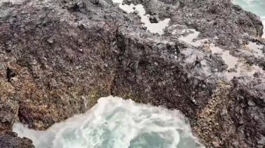 İnanılmaz volkanik kaya oluşumları muhteşem bir şekilde yükseliyor. Güzel sahil ortamında dalgalar onlara çarpıyor.