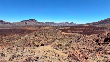 Engebeli dağlar ve canlı renklerin yer aldığı geniş bir volkanik arazinin nefes kesici ve çarpıcı manzarasına tanık olun.