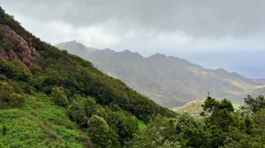 Yumuşak bulutlar ve canlı yemyeşil örtülü görkemli dağların nefes kesici ve çarpıcı manzaraları.
