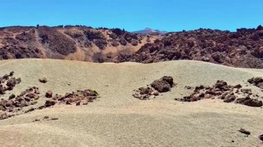 Açık mavi gökyüzünün altındaki engebeli arazinin çarpıcı manzarası doğanın büyüleyici güzelliğini gözler önüne seriyor.