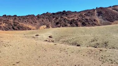 Berrak mavi gökyüzünün altında kayalık tepelerin yer aldığı uçsuz bucaksız, çorak bir arazi, kurak doğayı gözler önüne seriyor..
