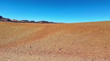 Parlak mavi gökyüzünün altında turuncu ve kahverengi renkleri olan kurak ve güzel bir manzara doğanın enginliğini gözler önüne seriyor..