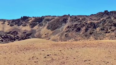 Açık mavi gökyüzü altında çarpıcı jeolojik oluşumların yer aldığı bu nefes kesici çöl alanını keşfedin..