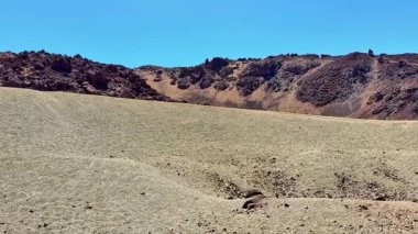Nefes kesen manzara, canlı mavi gökyüzünün altında güzel bir şekilde kurulmuş kuru, engebeli, kayalık bir arazi sergiliyor.