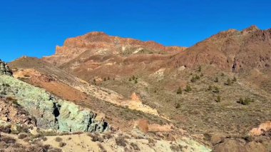 Uçsuz bucaksız çölde mavi gökyüzünün altındaki renkli dağların çarpıcı manzarası unutulmaz bir deneyim sunuyor.