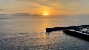 Nefes kesici ve güzel bir gün batımı, sakin suların yüzeyine yansıyan, huzurlu bir limana altın renkler saçar.