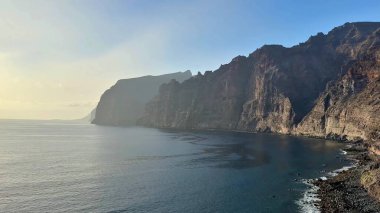 Sersemletici sahil kayalıkları heybetli bir şekilde sakin, sakin sularla karşılaşıyor güzel, resim gibi bir deniz manzarası.