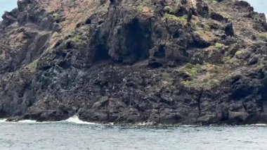 Çarpıcı manzarada berrak turkuaz sular ve canlı yemyeşil sularla çevrili engebeli bir ada yer alıyor.