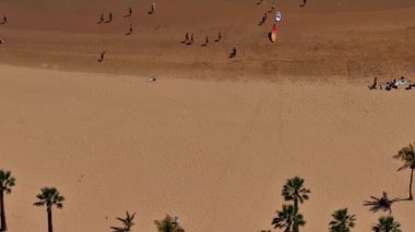 Altın kumlu, heyecan verici su sporları ve yaz güneşinin tadını çıkaran güneşli bir plaj sahnesi.