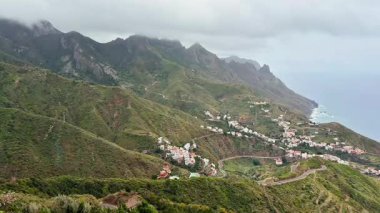 Bereketli dağların nefes kesici manzarası ve bulutlu gökyüzünün altında yuva yapmış büyüleyici bir kıyı köyü.