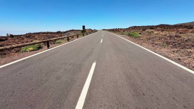 Geniş ve manzaralı bir manzara. Uzun, boş bir yol. Sert ve engebeli bir volkanik arazi boyunca uzanıyor.