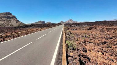 Güzel ve pitoresk bir yol eşsiz volkanik arazide yol alır, hepsi parlak, açık mavi bir gökyüzünün altında.