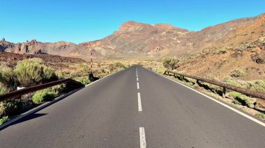 Çarpıcı bir çöl manzarasında görkemli dağlarla çevrili dolambaçlı bir yolun nefes kesici manzarası..