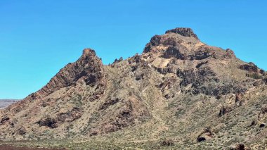 Nefes kesen manzara, parlak mavi gökyüzünün altında engin bir çöl ortamında geçen engebeli bir dağ sırasını gözler önüne seriyor.