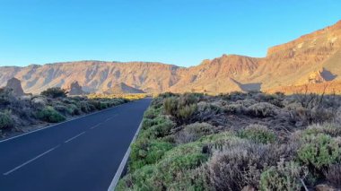 Engebeli dağlar ve canlı bitki örtüsüyle çevrili dolambaçlı bir yola sahip çarpıcı, güzel bir manzara.