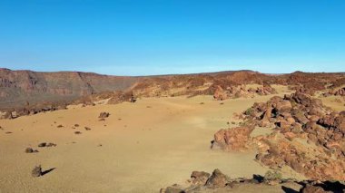 Uçsuz bucaksız ve geniş bir çöl, kayalık arazisini açık mavi gökyüzüne vurguluyor.