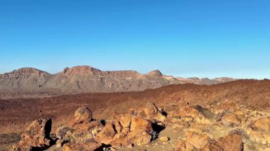 Yüksek kayalık dağların nefes kesici manzarası ve sakin ve sakin çöl manzarasında berrak mavi bir gökyüzü.