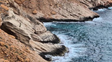 Çarpıcı kıyı manzaraları, okyanusun büyüleyici türkuaz sularıyla buluşan engebeli uçurumları vurgular.