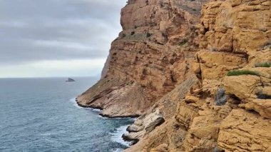 Sarp, engebeli kıyı uçurumlarının nefes kesici manzarası bulutlu gökyüzünün altında huzurlu denizi çarpıcı bir şekilde karşılıyor.