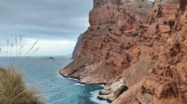 Engebeli uçurumların nefes kesici ve büyüleyici manzaraları bulutlu bir gökyüzünün altında sakin denizlerle çarpışıyor.