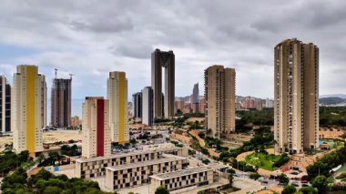 Canlı bir şehir manzarası çarpıcı ve hareketli gökyüzüne karşı modern gökdelenleri sergiliyor.