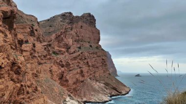 Sakin suların yanında, bulutlu gökyüzünün altında dimdik duran engebeli uçurumların çarpıcı manzarasını tecrübe edin.