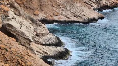 Çarpıcı kıyı manzaraları, okyanusun büyüleyici türkuaz sularıyla buluşan engebeli uçurumları vurgular.