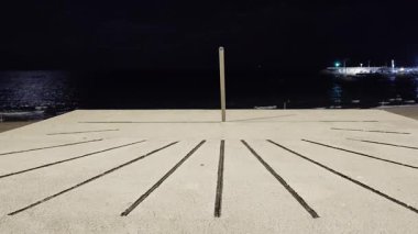 Bu video, gece okyanus kıyısında bir beton yüzeyde bulunan ve arka planda hafif dalgalar oluşturan bir güneş saati gösteriyor. 