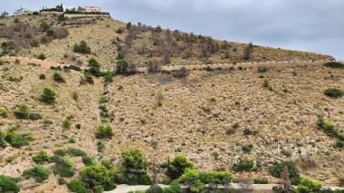 Tepedeki sakin bir ev yeşillik ve dolambaçlı bir yol ile çevrilidir. Seyircileri ona doğru huzurlu bir yolculuk hayal etmeye çağırır.