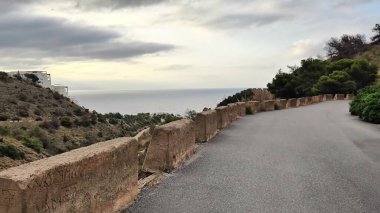 Bu büyüleyici video okyanusa açılan büyüleyici taş duvarlı manzaralı bir yol sergiliyor, nefes kesen kıyı manzaralarını gözler önüne seriyor