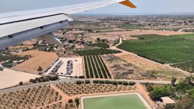 Bu hava görüntüsü bir uçak penceresinden çarpıcı görüntüler yakalıyor, canlı şehirlerden dingin yeşil alanlara geçiş, uçuşun güzelliğini gösteriyor