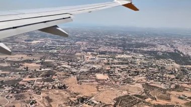 Canlı bir şehir manzarasının üstündeki bir uçaktan nefes kesici görüntüyü deneyimleyin, şehir simgelerinin üzerinde süzülen kanatları ve hareketli caddeleri yakalayın.