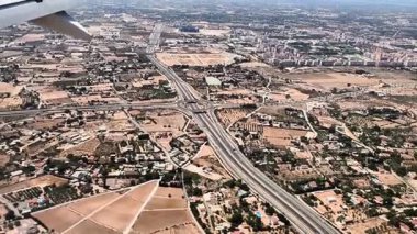 Bir uçak penceresinden hareketli bir şehrin nefes kesici hava manzarası. Karmaşık şehir yaşam şekilleri ve hareketli otoyollar.