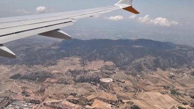 Bu hava görüntülerinde çeşitli manzaralarda süzülen bir uçak kanadı, görkemli dağlar ve sakin vadileri gözler önüne seriyor, dünyaların güzelliğini vurguluyor.