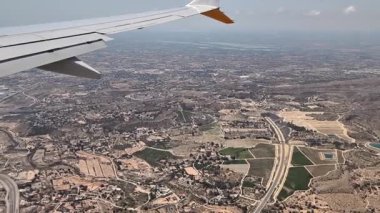 Çarpıcı bir hava perspektifi, bir uçak kanadından geniş alanlarla birlikte kentsel bir manzara ortaya çıkarıyor.