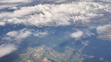 Bu hava manzarası yeryüzünün yukarısından görülen yemyeşil manzaralar ve büyüleyici bulut oluşumlarını sergiliyor.