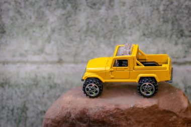 Kahverengi kayalık yüzeyde sarı minyatür 4x4 kamyonet. Dağ sürüşünü taklit etmek için tasarlanmış. Oyuncu off-road macera teması için bulanık arkaplanı olan yüksek açı bileşimi.