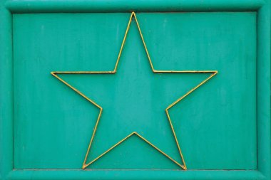 Çerçevenin içinde beş köşeli dekoratif altın yıldızlı yeşil boyanmış metal panelin yaratıcı metalik arka planı. Endüstriyel vintage tarzı arka plan tasarım projeleri, retro afişler veya yaratıcı dekorasyon fikirleri için mükemmel.