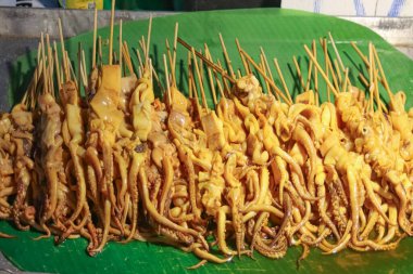 Tayland 'da bir gece marketinde muz yaprakları üzerinde sunulan leziz ızgara kalamar şişleri, otantik Güneydoğu Asya lezzetleri ve aşçılık turizmini temsil ediyor..